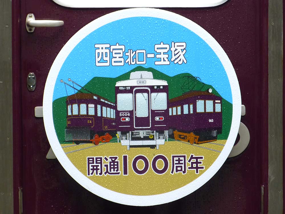阪急今津線「西宮北口～宝塚駅間」開通100周年記念ヘッドマーク（西宮北口側に掲出）。51形、5000系、90形のイラストが掲載されています。